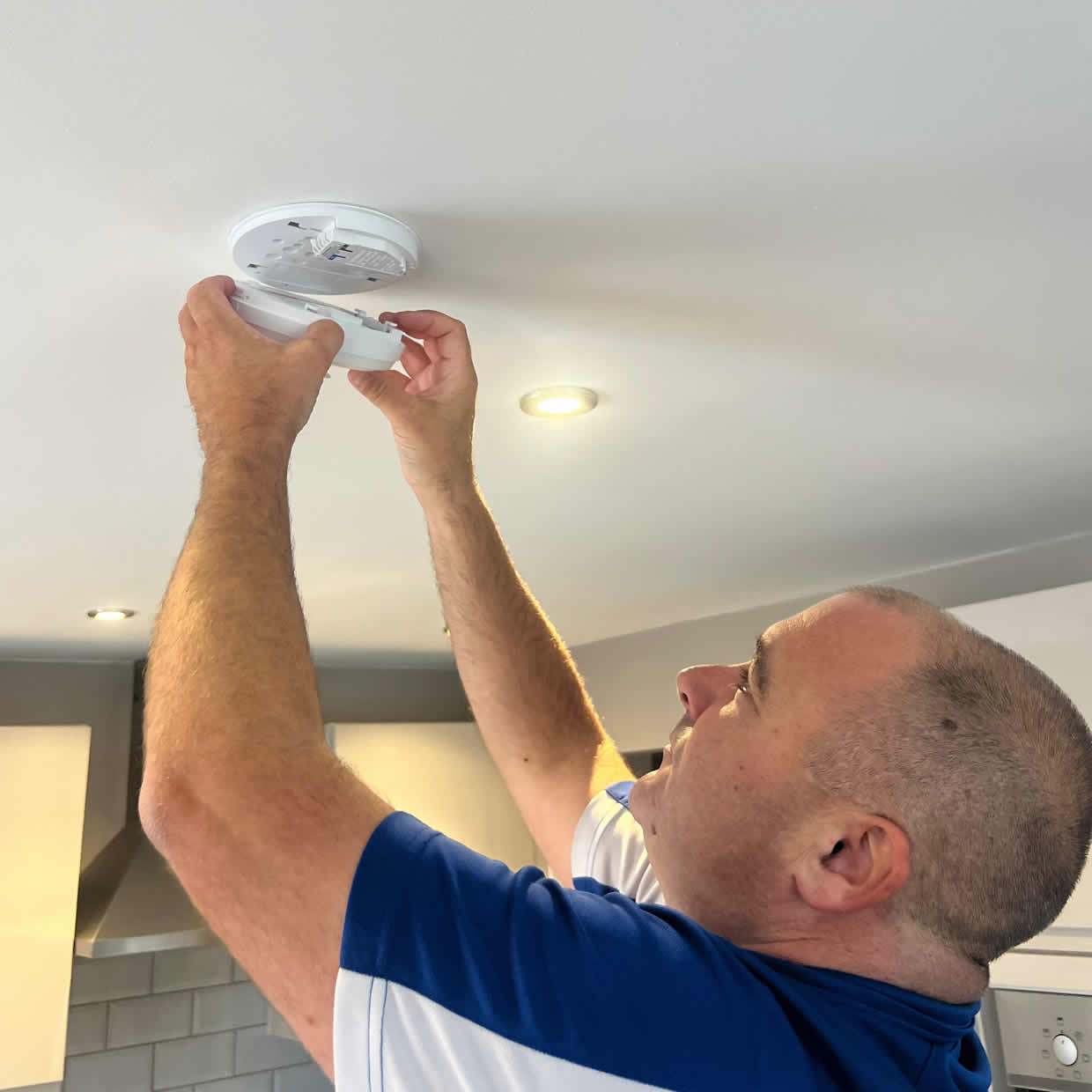 Smoke alarm installer fitting an alarm in a Sutton Coldfield property